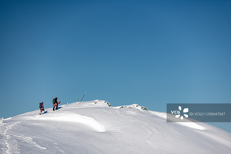 单板滑雪者徒步登上山顶图片素材