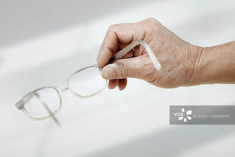 老年男人拿着眼镜的手图片素材