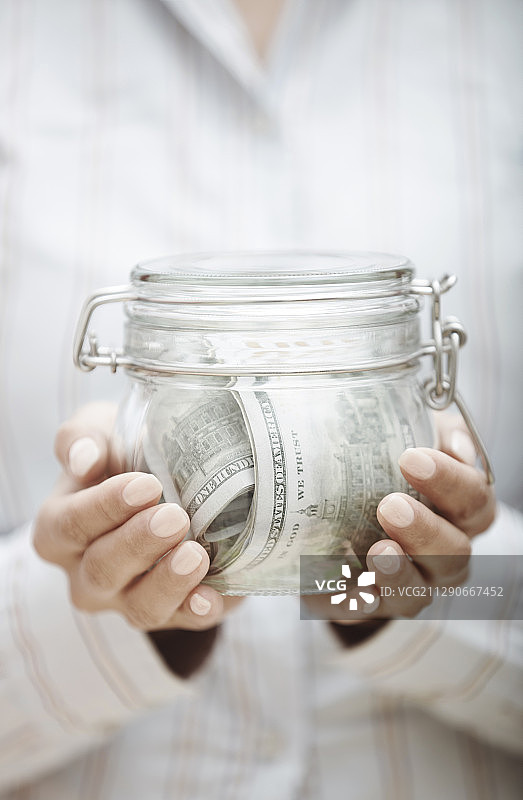 女人拿着装有美元的玻璃罐图片素材