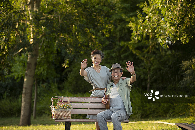 老年夫妻在公园长椅上打招呼肖像图片素材