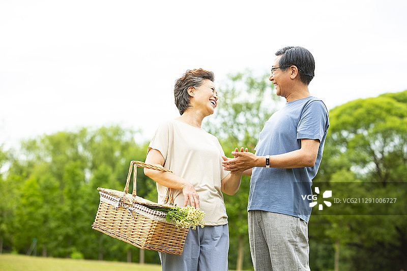 老年夫妻提着野餐篮子准备去公园郊游野餐图片素材