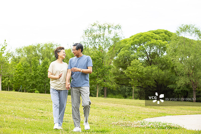 老年夫妻手牵手在户外公园散步图片素材