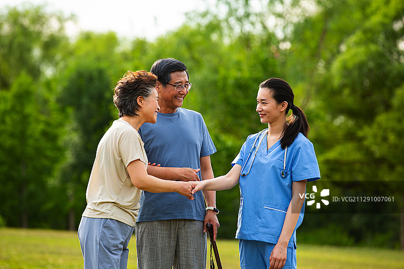 老年夫妻和女医生在户外疗养院的公园里握手图片素材