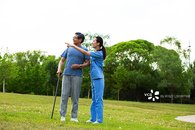 老年男人和女医生在户外疗养院的公园里散步聊天图片素材
