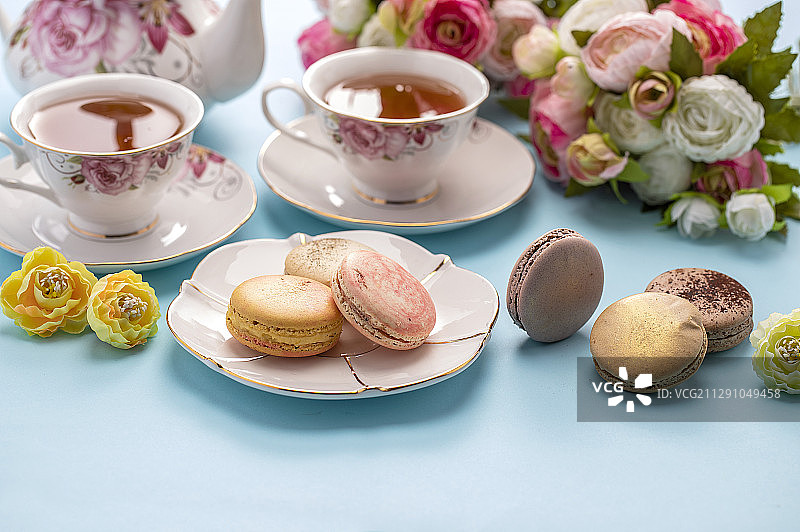 红茶和许多色彩鲜艳的马卡龙摆放在桌上图片素材