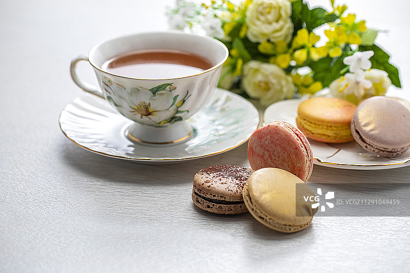 红茶和许多色彩鲜艳的马卡龙摆放在桌上图片素材