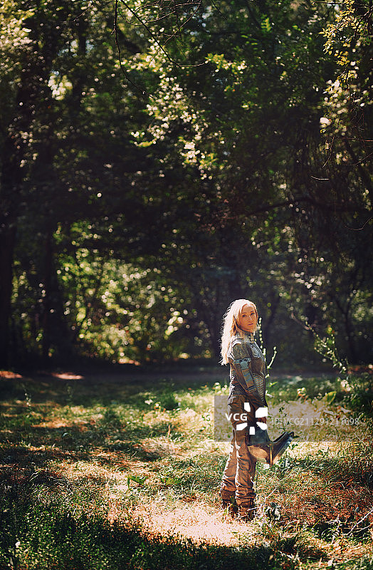 身穿太空服的女宇航员在森林中手持头盔图片素材