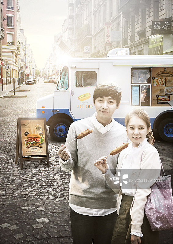 情侣在城市餐车旁吃玉米热狗图片素材