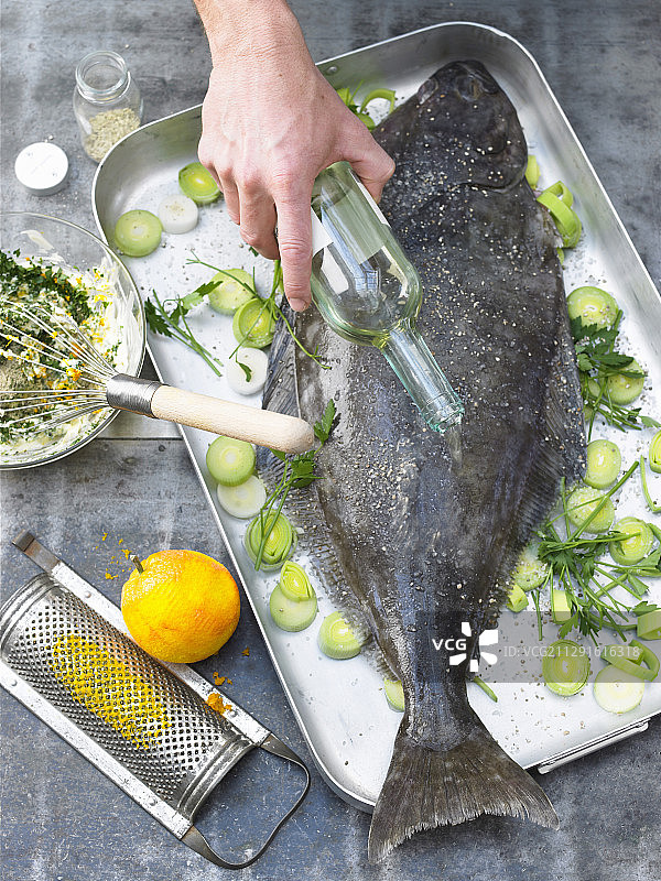 将白葡萄酒倒在整条大比目鱼上图片素材