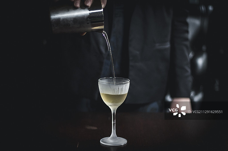 将透明的咖啡鸡尾酒从摇壶倒入玻璃杯中图片素材