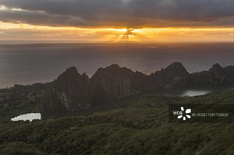 南太平洋上空，新喀里多尼亚林德拉里克岩石后突破云层的阳光图片素材