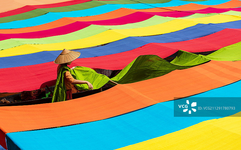 在缅甸塔亚瓦底，一人准备用莲花手工制作的彩色织物的侧面视角图片素材