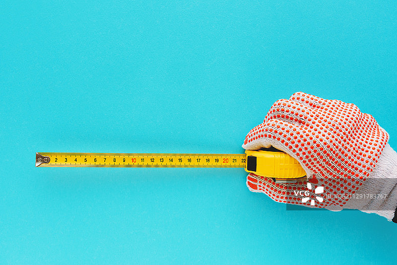 工人在蓝色背景上用卷尺测量尺寸（塞尔维亚诺维萨德）图片素材