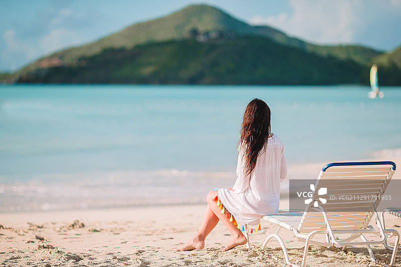 夏季海滩上坐在躺椅上的女人背影图片素材
