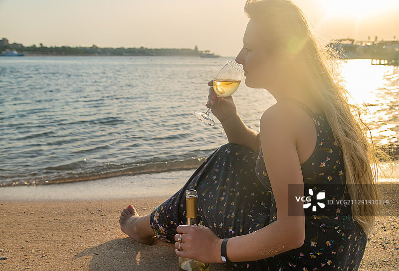 年轻女人在海边喝葡萄酒图片素材