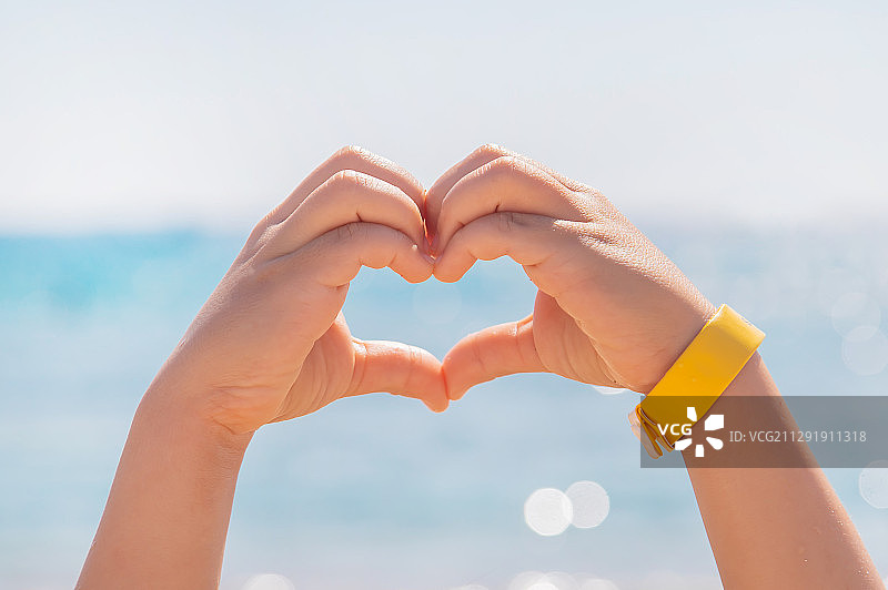 女孩在海边用手比心特写图片素材