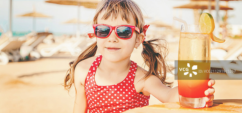 穿红色泳衣的女孩在海滩上喝清凉饮料图片素材