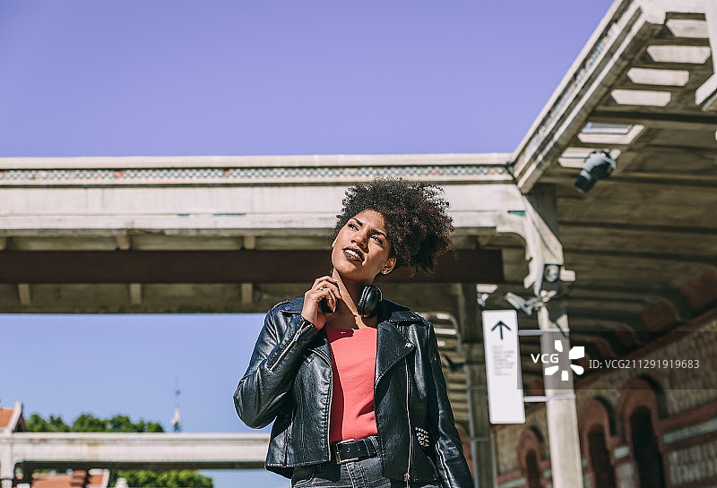 戴着耳机和黑色夹克的思考的非裔美国妇女图片素材