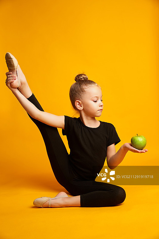 穿紧身衣伸腿拿绿苹果的女孩图片素材