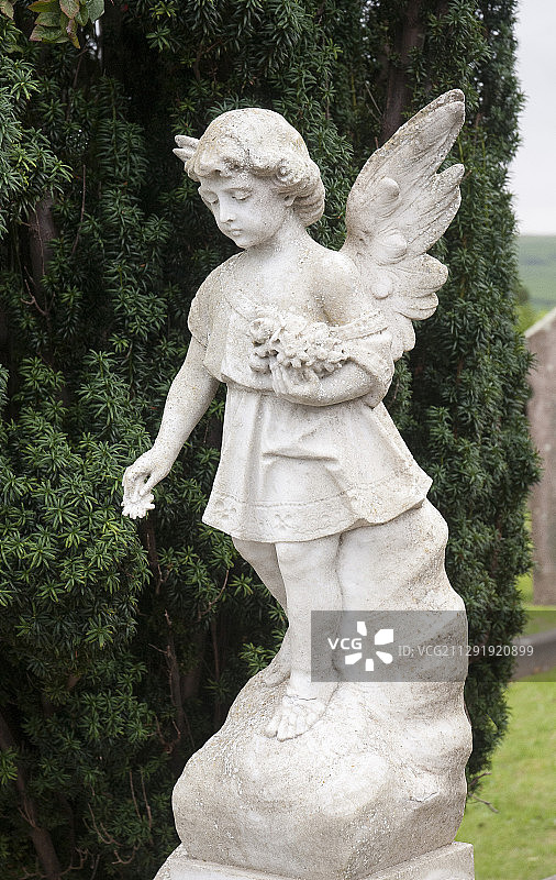 绿色树木背景下的白色大理石天使雕像图片素材