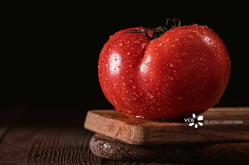 黑色背景上带有水滴的番茄特写图片素材