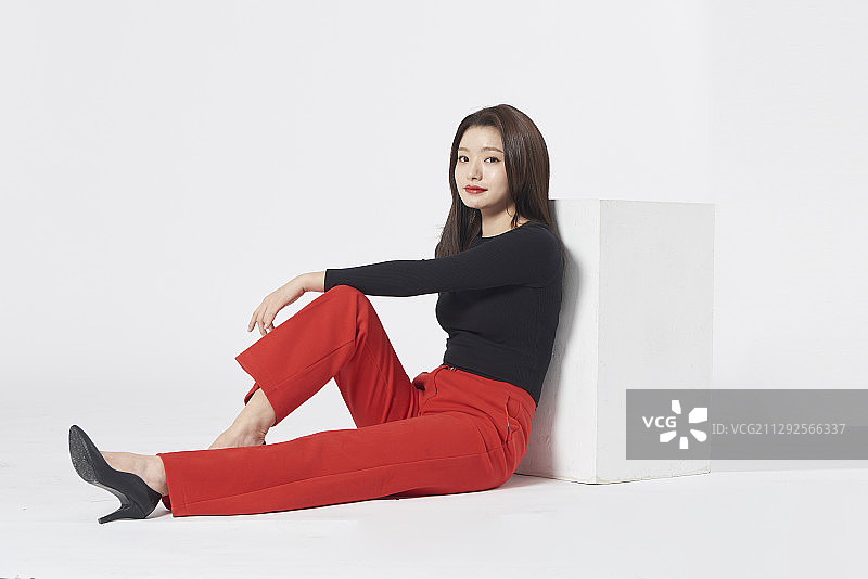 靠在椅子上，手放在腿上的女子（影棚拍摄）图片素材