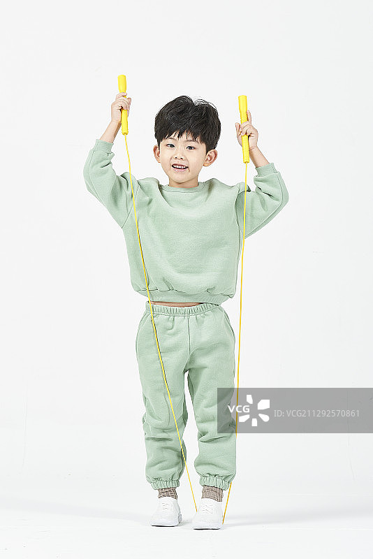 站在白色背景下手持跳绳的男孩的影棚照片图片素材