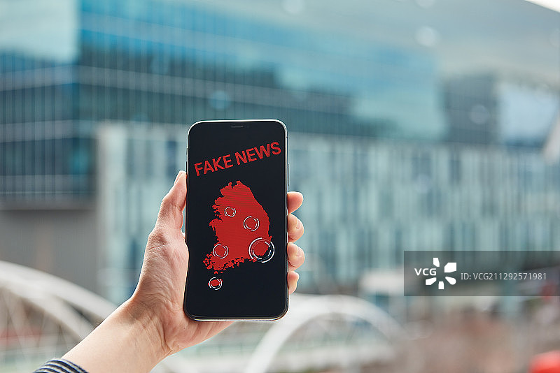 户外手持带假新闻信息的智能手机摄影照片图片素材