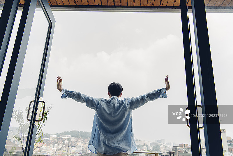 男人早上在阳台上伸展双臂的照片图片素材