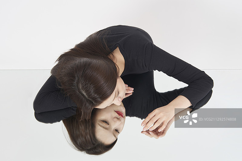 女人靠在镜子前看着镜子的影棚照图片素材