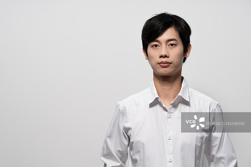 在白色背景前，穿白色衬衫的年轻男人图片素材
