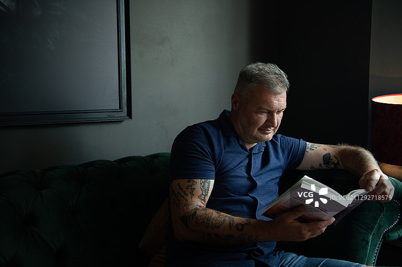 在客厅里看书的纹身男人图片素材