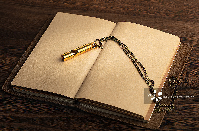 打开的复古笔记本上的金色口哨图片素材