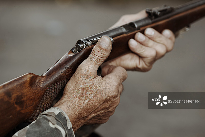 穿着迷彩服的猎人拿着猎枪的手图片素材