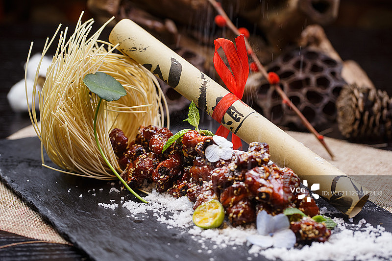 黑色石盘装的广式蜜汁叉烧小排骨摆放在麻布垫上图片素材