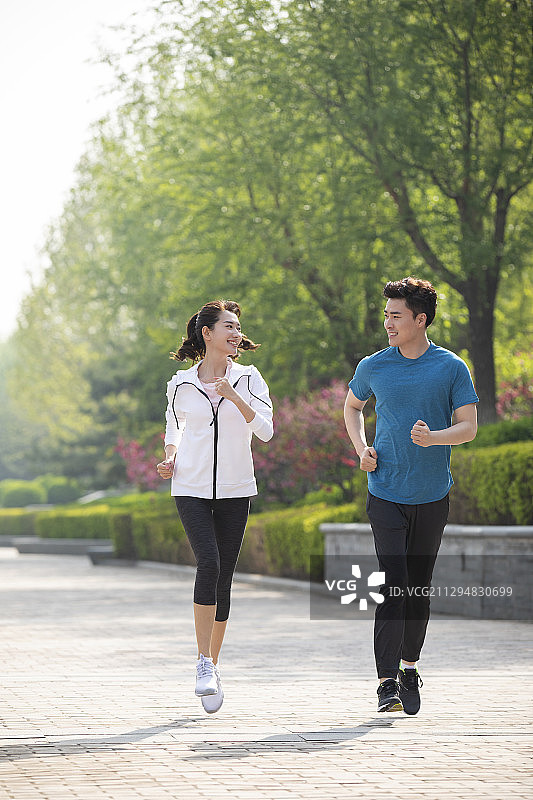 快乐的年轻情侣在公园跑步图片素材