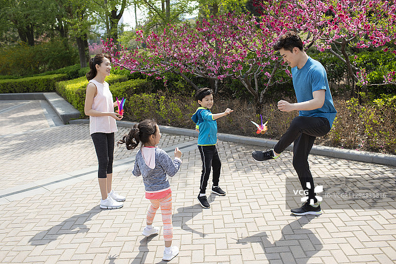 快乐的年轻家庭在公园踢毽子图片素材