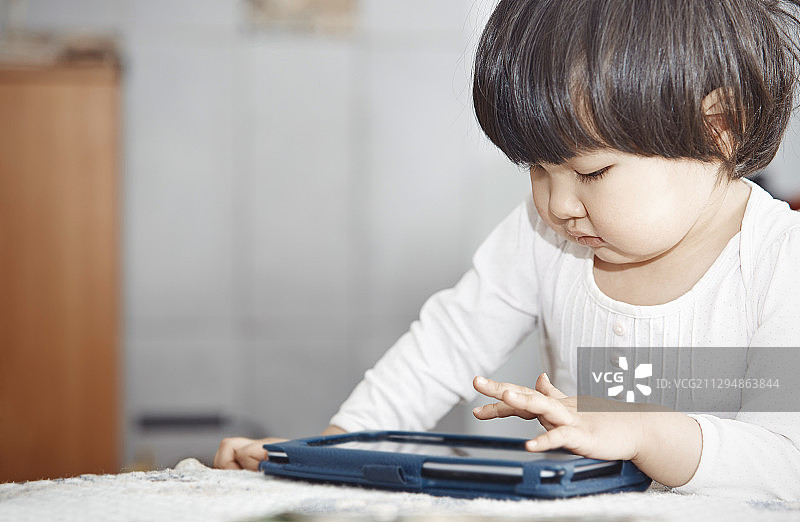 在家玩平板电脑的2岁儿童图片素材