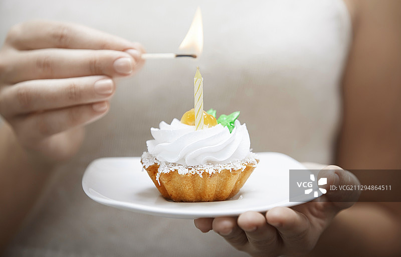 女人点燃蛋糕上的蜡烛图片素材