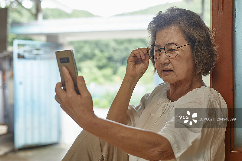70岁老人智能手机数字延迟视频通话老花眼图片素材