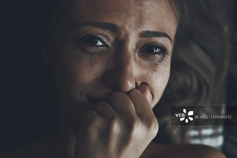 沮丧的年轻女子躺在床上哭泣图片素材