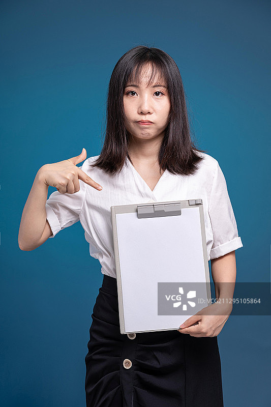 深蓝色背景前，拿着A4纸纸夹的女性职员1图片素材