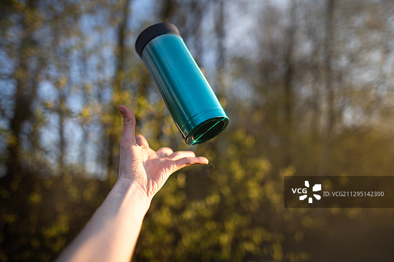女子手持可重复使用的旅行杯特写，树木背景，波兰图片素材