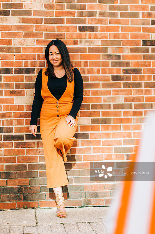 站在美国阿灵顿高地砖墙前的微笑年轻女子肖像图片素材