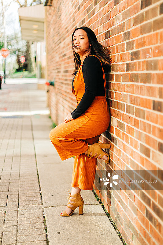 倚靠在砖墙上的年轻女子肖像，美国阿灵顿高地图片素材