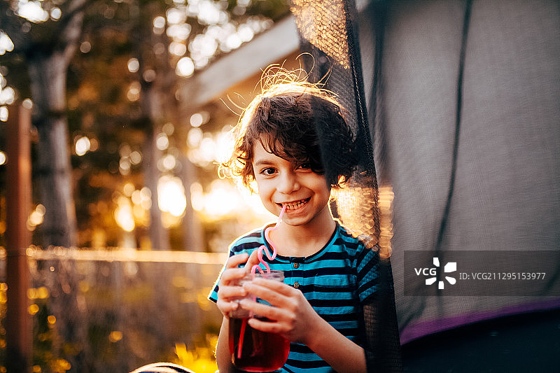 笑容灿烂的男孩坐在加拿大维多利亚的院子里，手里拿着饮料图片素材