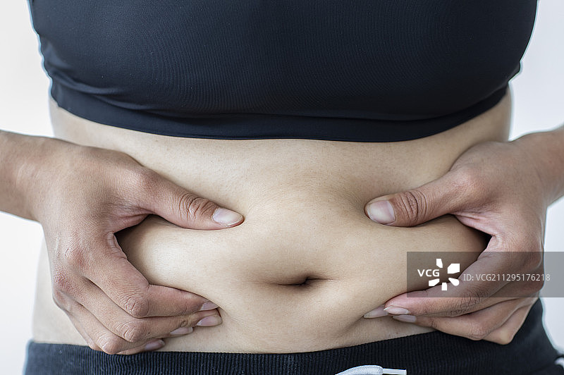 东方女性用手捏自己肚子上的肥肉图片素材