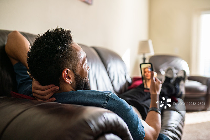 黑人男子在家中沙发上使用手机图片素材