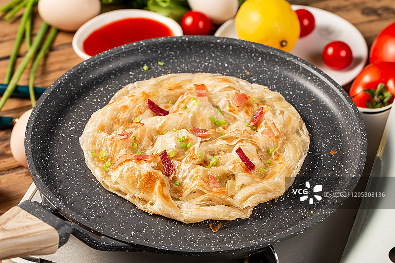 一片美味手抓饼放在木板背景上的平底锅里图片素材