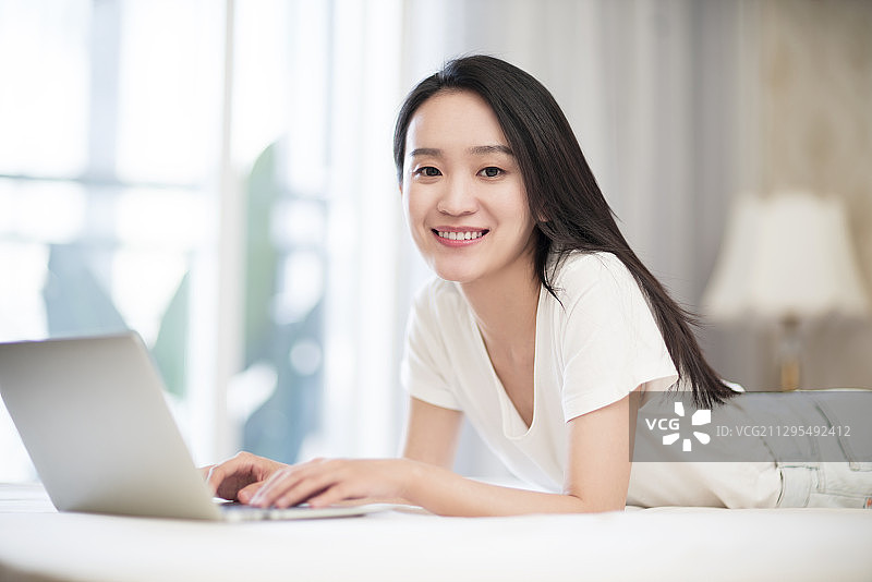 年轻女子在床上使用笔记本电脑图片素材